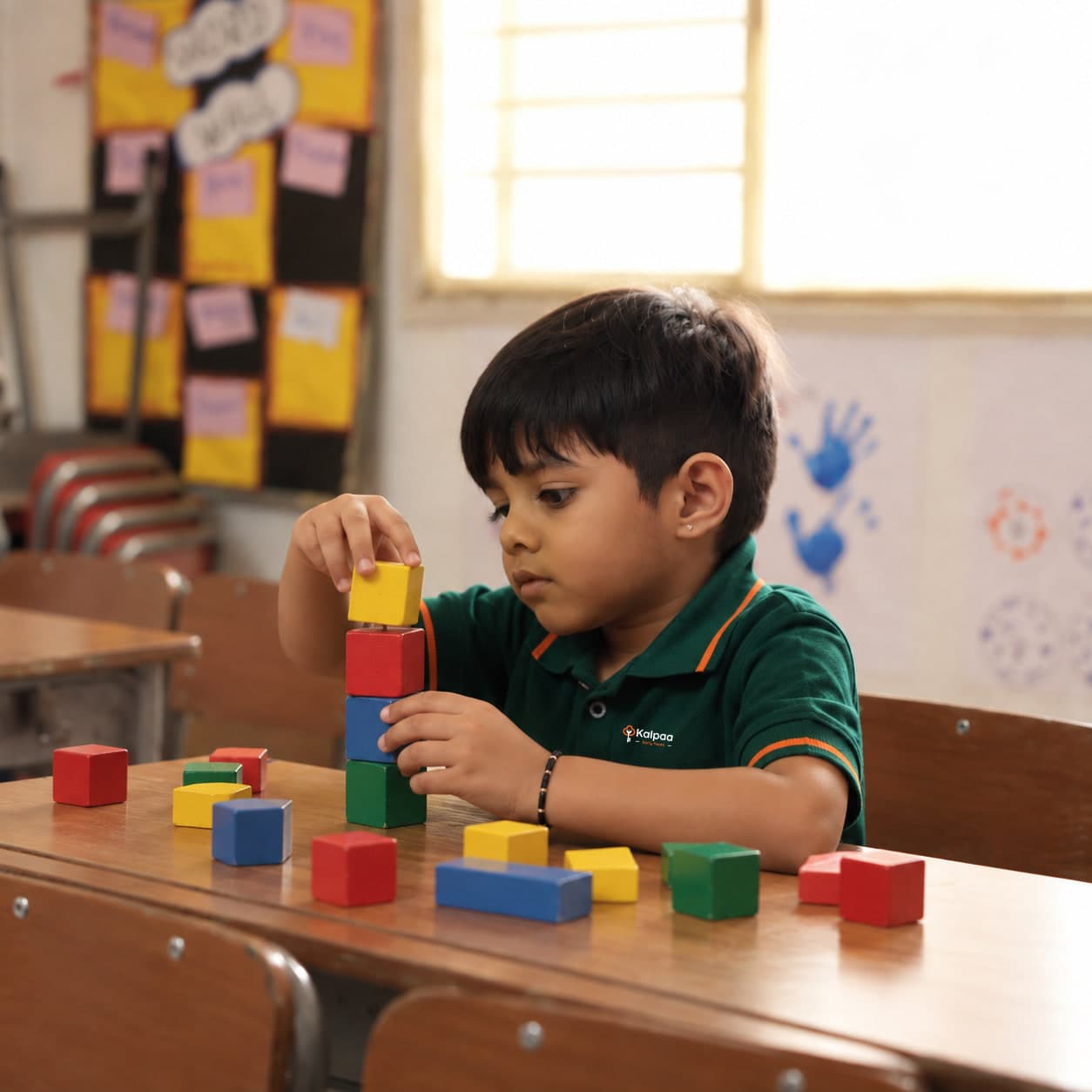 A child stacking wooden blocks into a tower at his desk