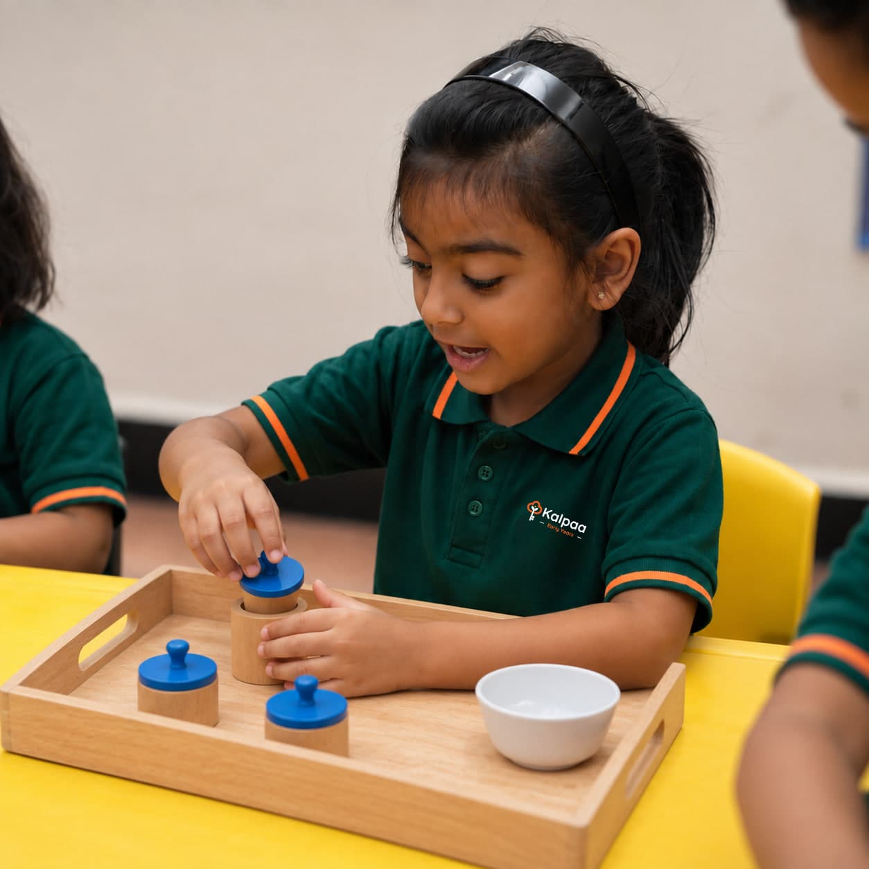A child working through a tray of knobbed cylinders