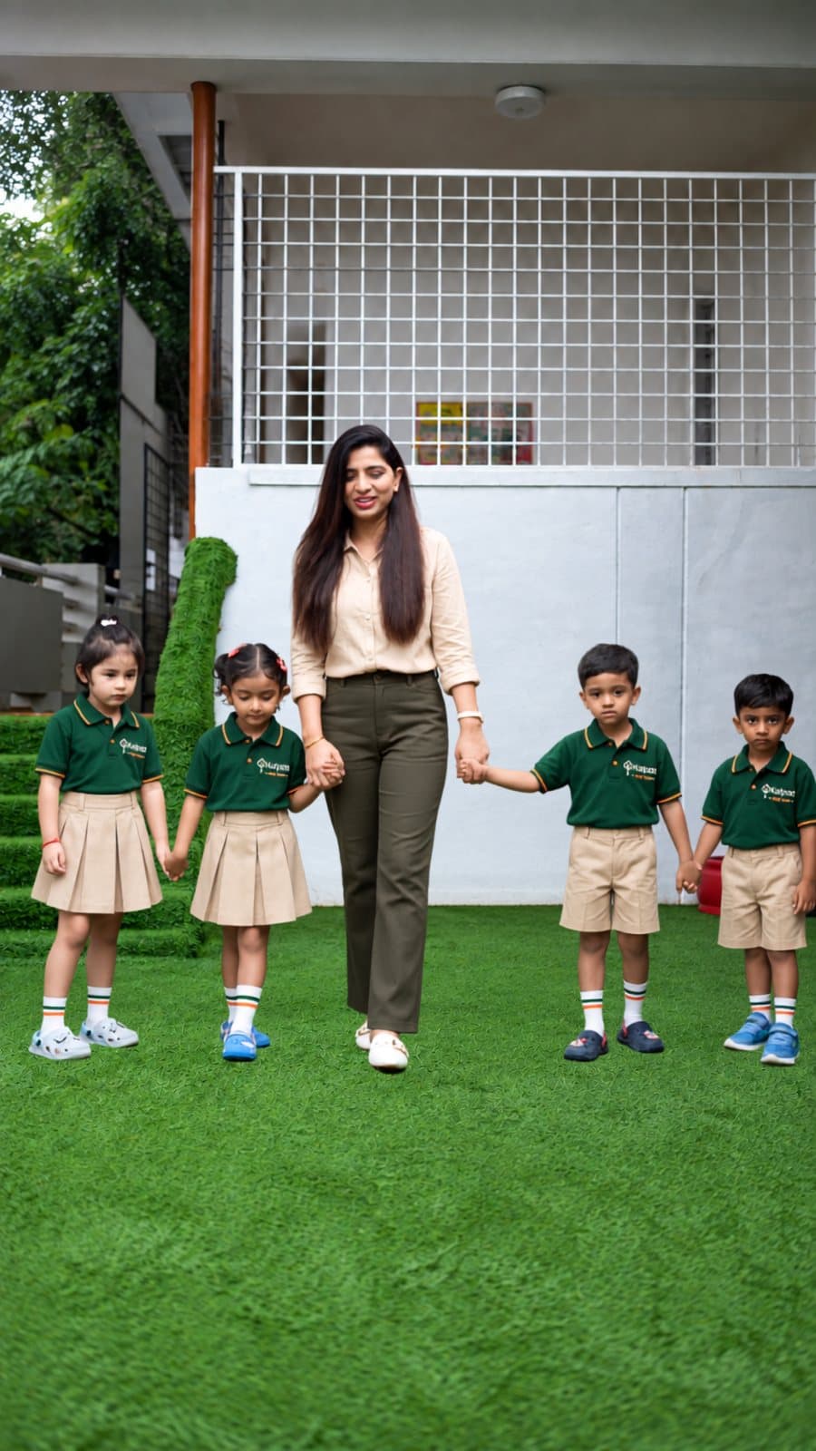A Kalpaa teacher walking hand in hand with four children across the centre's lawn